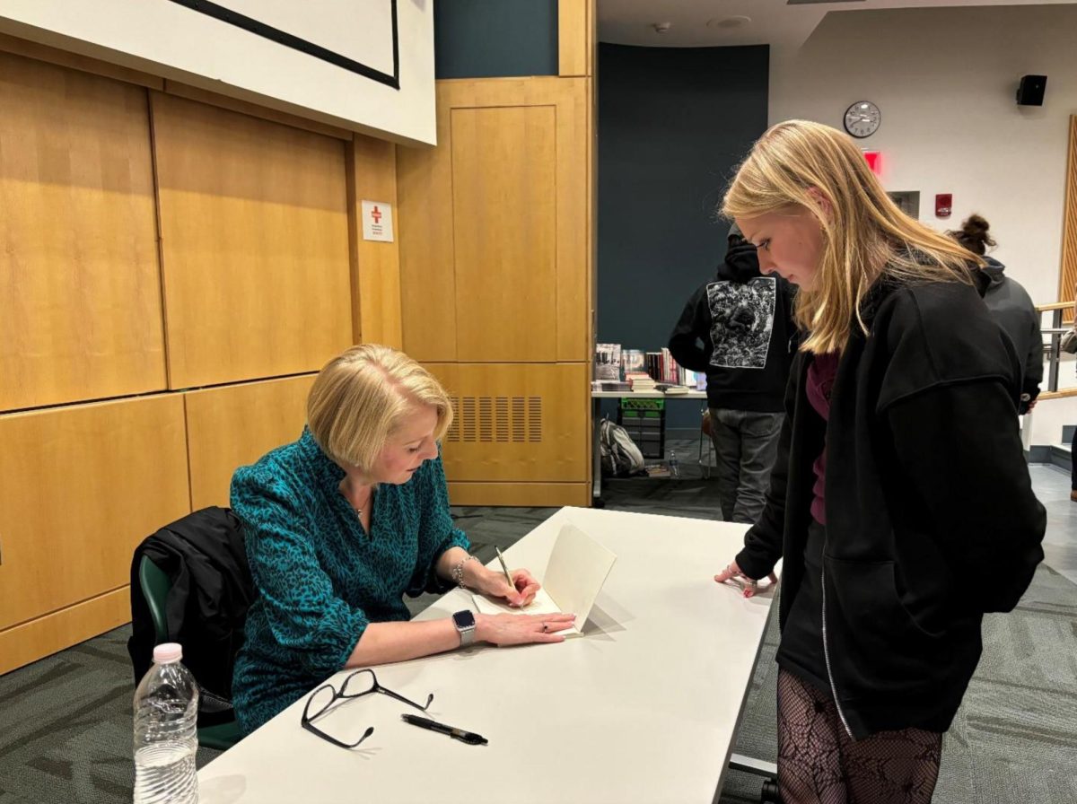 Published writer Heidi Slettedehl signing her book provided by SUNY Brockport student Madeline Rodger at the Writers Forum 