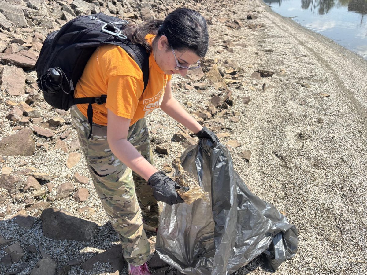 Jamie Hoffman picking up trash in the canal (Duncan Harbin, April 22, 2026) 